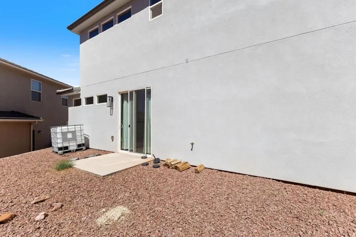 Stucco exterior with multiple windows, a concrete patio, and a sliding glass door