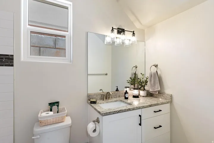 White vanity with a granite-style countertop and undermount sink