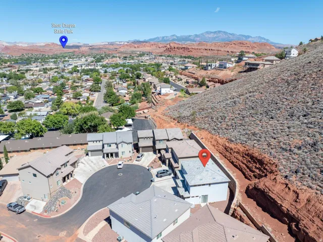 New construction residences with pitched roofs, situated on a cul-de-sac, surrounded by expansive desert terrain and distant mountains