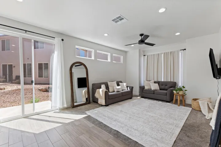 Sliding glass door leading to the outdoor space, recessed ceiling lighting, ceiling fan, and multiple transom windows