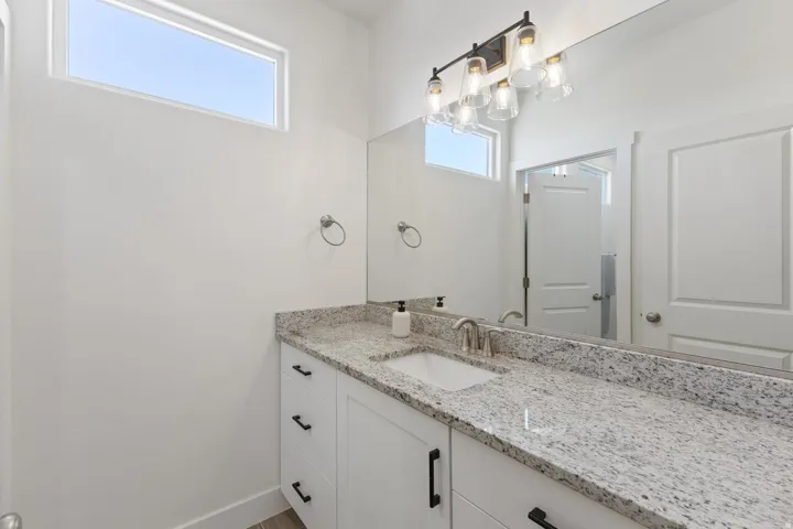 White vanity with a granite-style countertop and an undermount sink