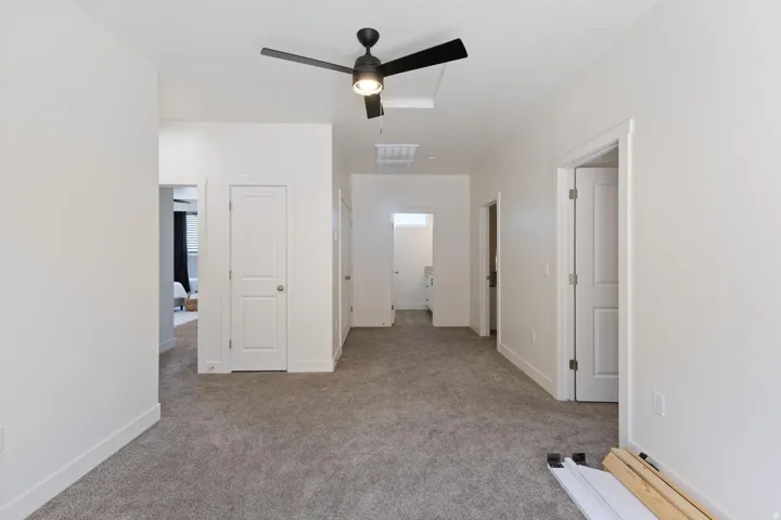Light grey carpeting, white painted walls, and a black ceiling fan with integrated lighting