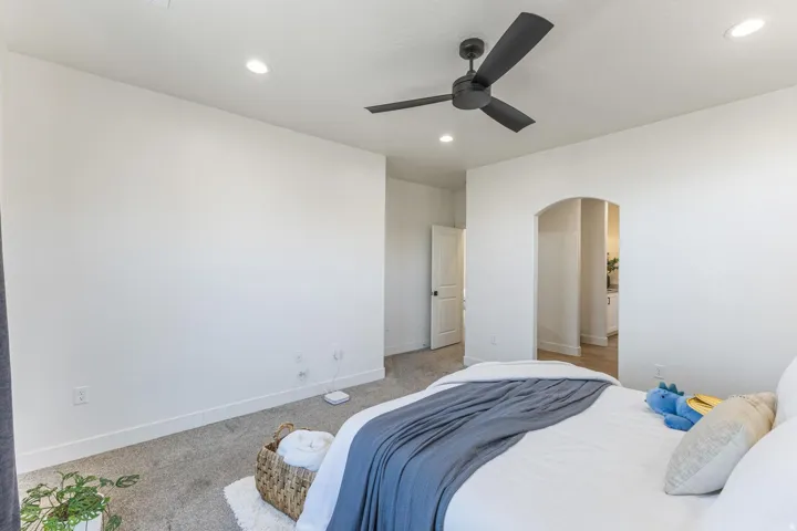 Neutral wall finishes, recessed lighting, ceiling fan, arched doorway, and carpet flooring