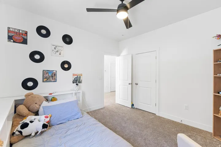 Built-in shelving, ceiling fan, neutral carpet, white trim, and a wood-finish bookcase