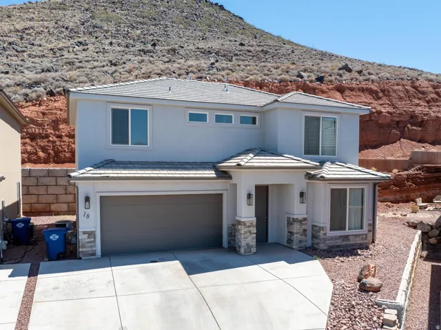 Two-story residence featuring a tile roof, stucco exterior, stone accents, and an attached two-car garage