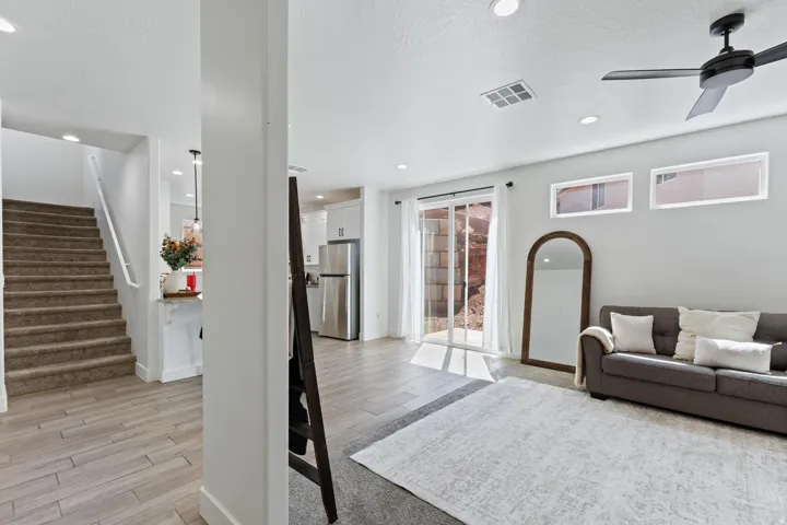 Open-concept living space with wood-finish flooring, a ceiling fan, recessed lighting, and a sliding glass door