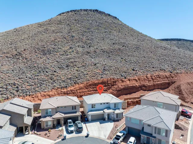 Contemporary residence with a multi-tone exterior, attached two-car garage, and a tiled roof, situated against a rugged, natural desert landscape