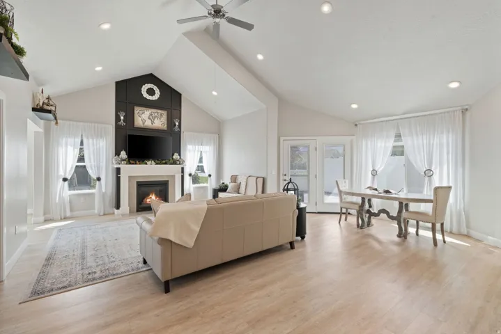 Vaulted ceilings, recessed lighting, wood-finish flooring, fireplace with mantel, and French doors