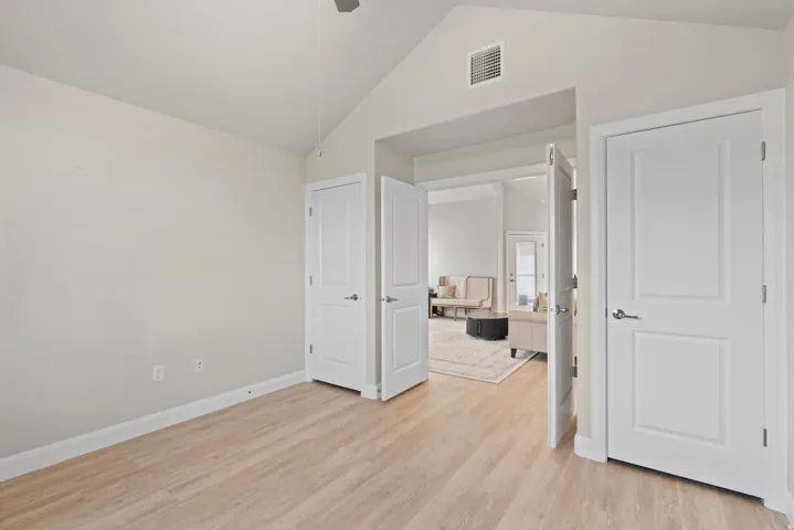 Vaulted ceiling, wood-finish flooring, and white paneled doors
