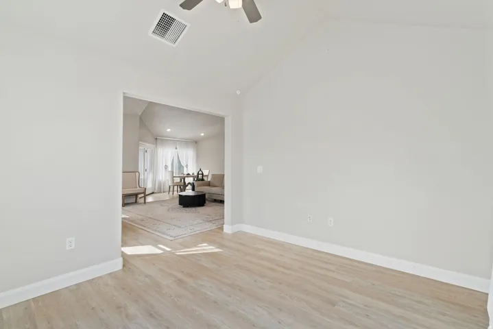 Vaulted ceiling, ceiling fan, neutral wall tones, wood-finish flooring, cased doorway