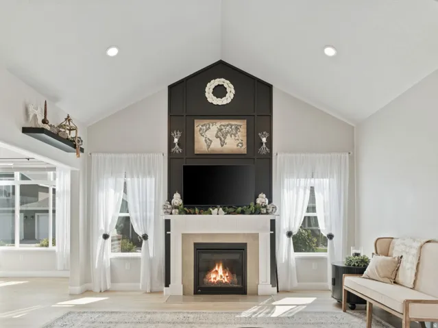Vaulted ceiling, recessed lighting, and a prominent fireplace with a white mantel and dark accent surround