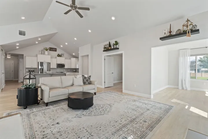 Vaulted ceiling with recessed lighting and ceiling fan, wood-finish flooring, white cabinetry, and stainless steel appliances