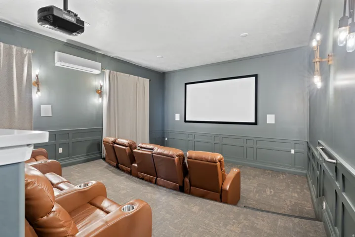 Dedicated media room with wall paneling, built-in projection screen, and a ceiling-mounted projector located in Community Clubhouse