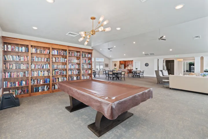 Expansive common area featuring a vaulted ceiling, recessed lighting, and built-in wood shelving