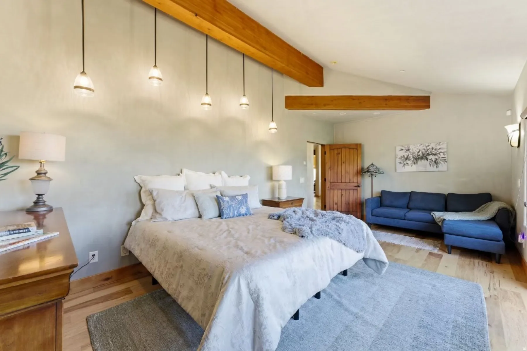 Vaulted ceiling with exposed wood beams, wood-finish flooring, and pendant lighting