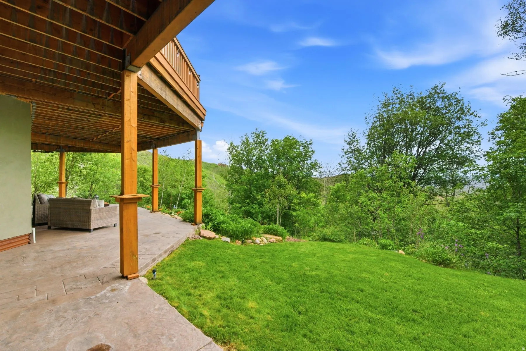 Expansive green lawn, bordered by mature trees and natural landscaping