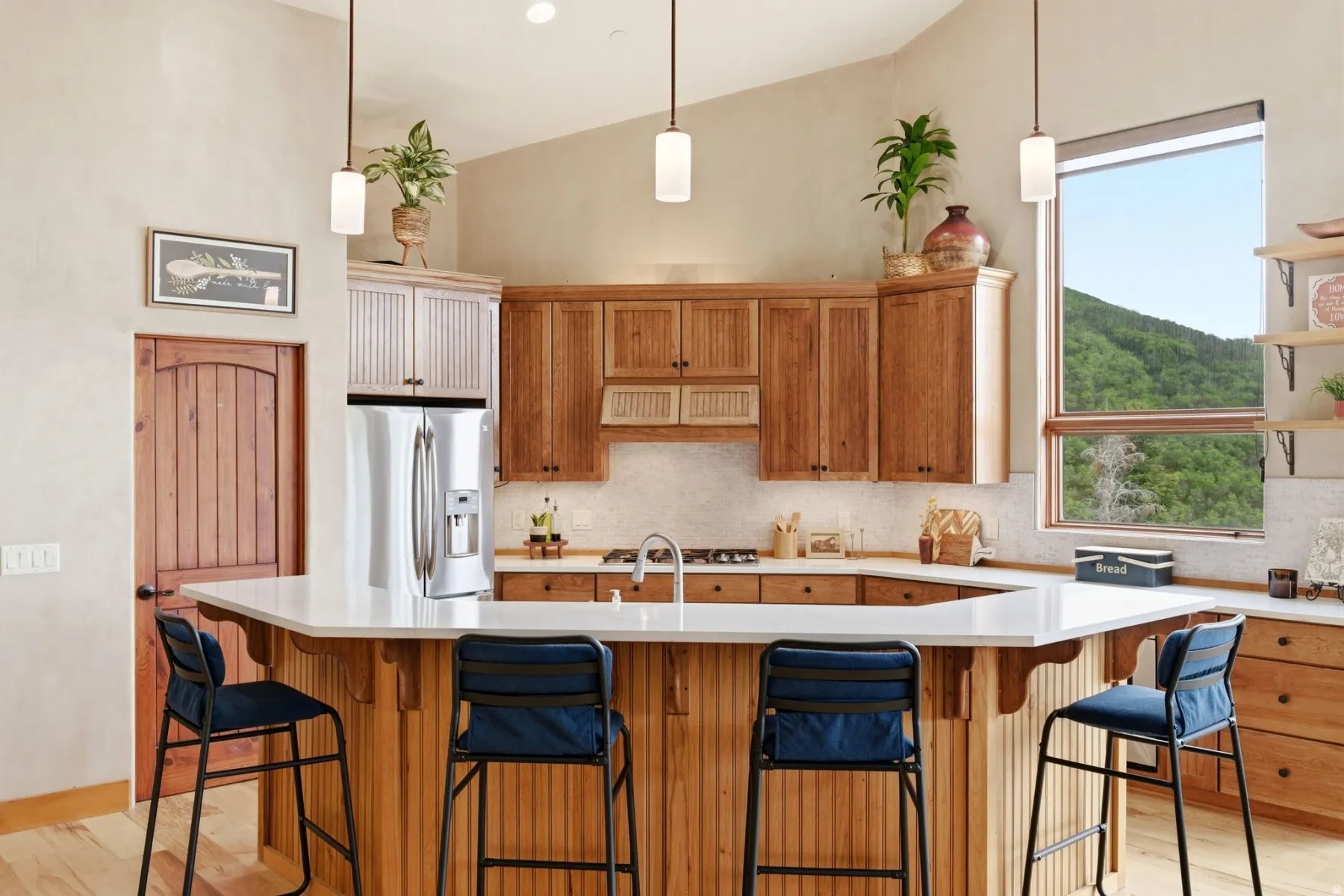 Vaulted ceilings, wood-finish cabinetry, stainless steel refrigerator, white countertops, and integrated shelving