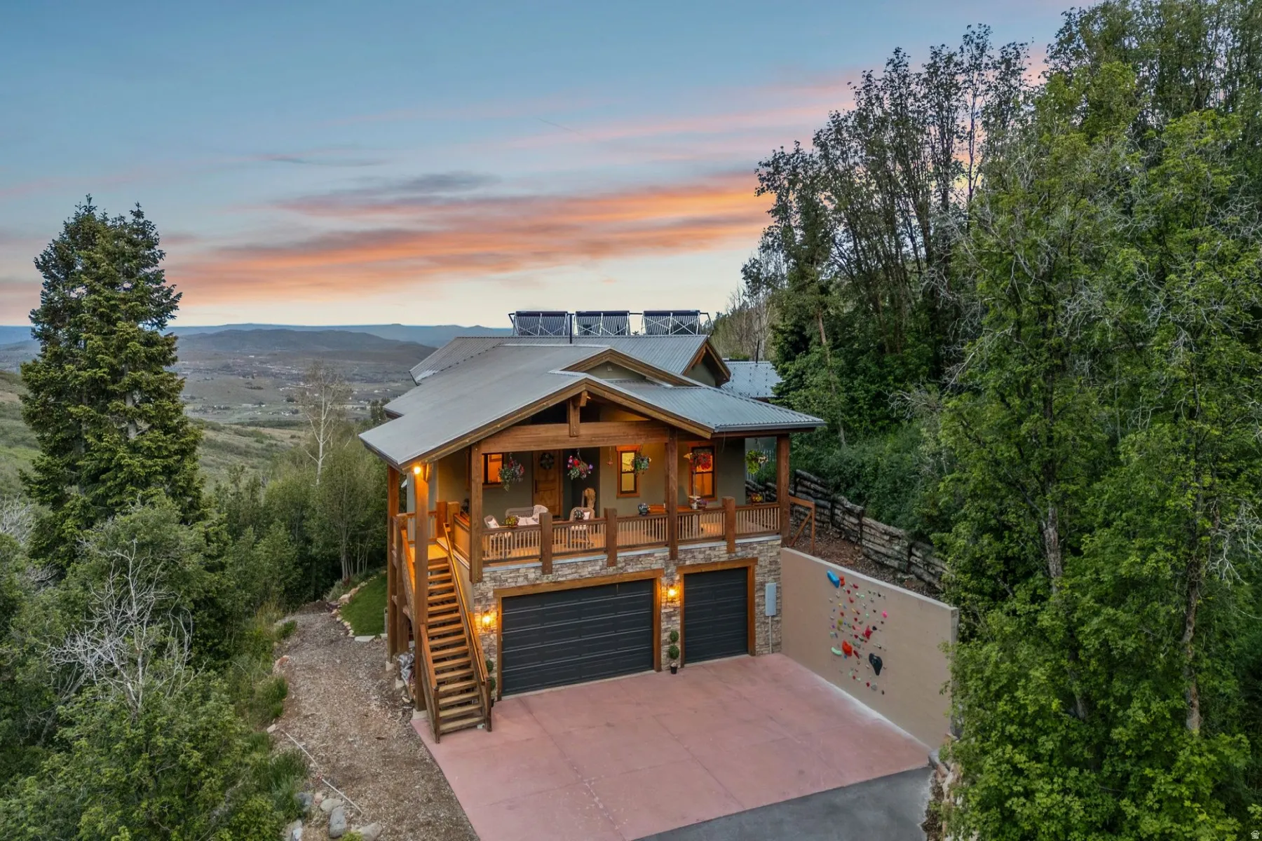 Multi-level residence featuring a stone-clad lower level, a spacious outdoor deck, and two attached garage bays