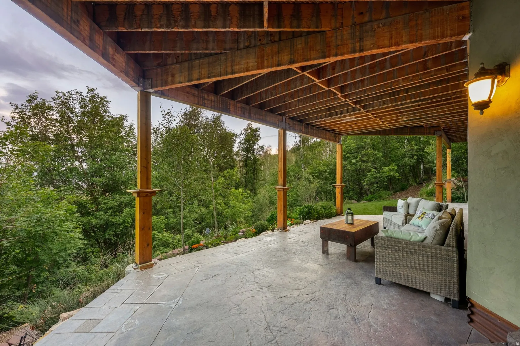 Covered patio featuring an exposed wood beam ceiling, wood support columns, and stamped concrete flooring