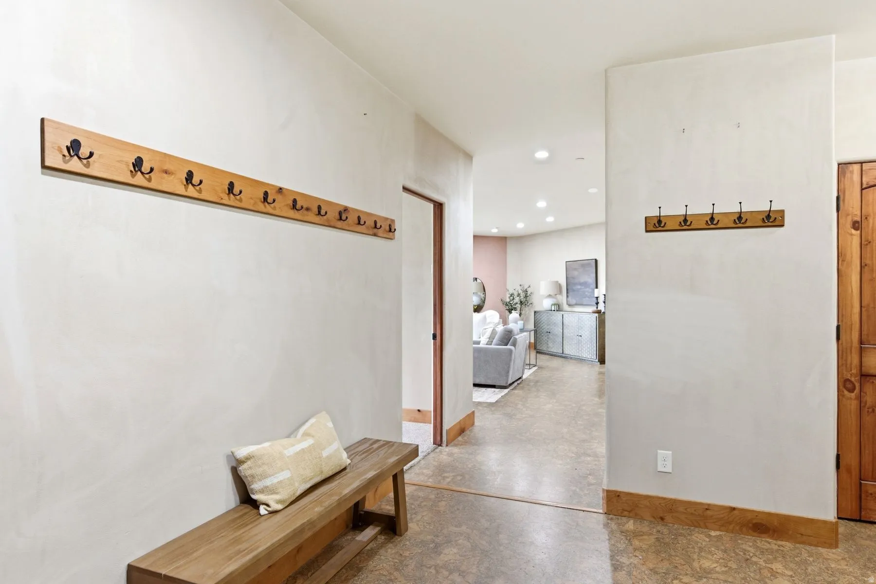 Entryway featuring wood-finish flooring, a built-in wood bench, and two wall-mounted coat racks