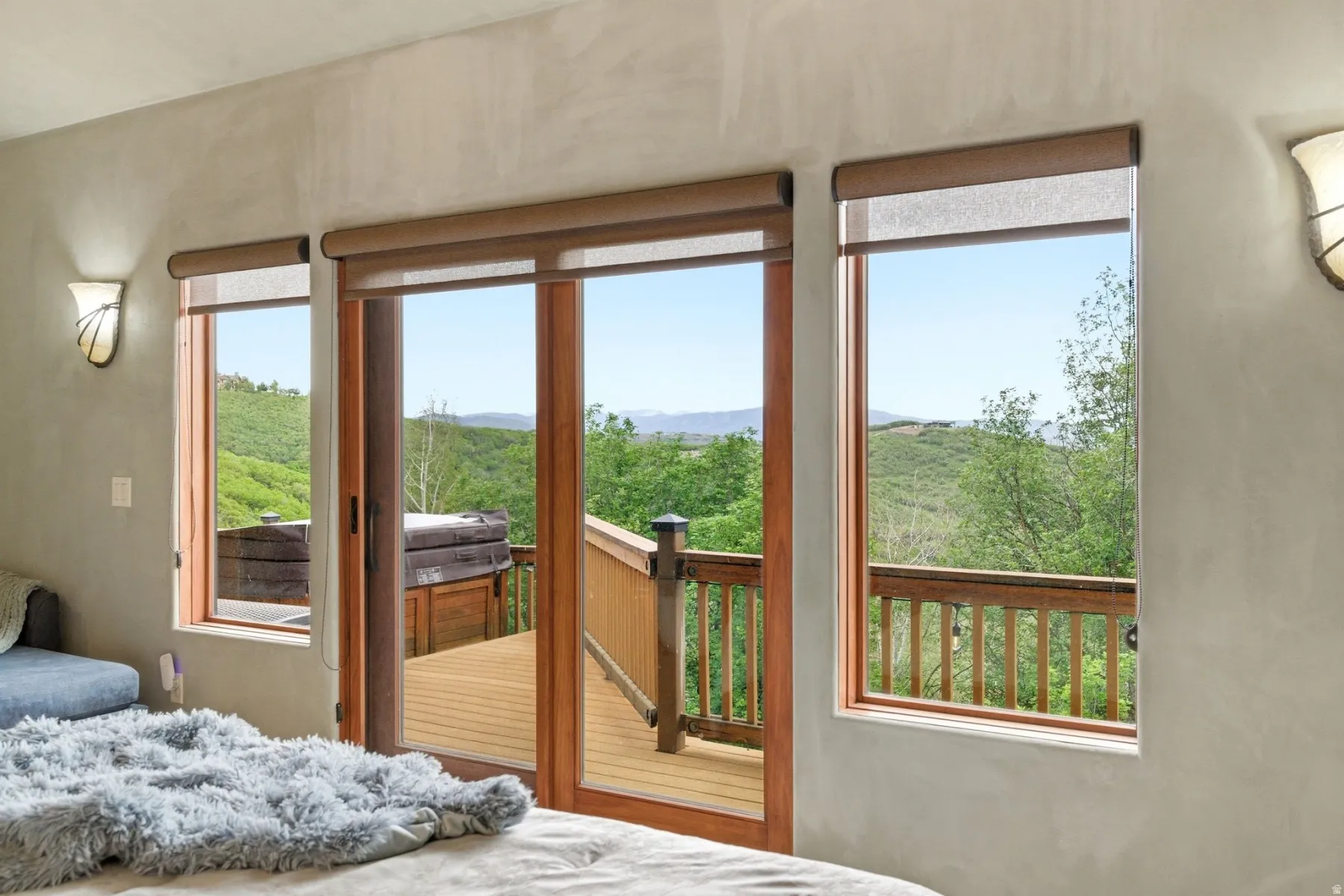 Wood-finish sliding glass doors open to an exterior deck with a hot tub