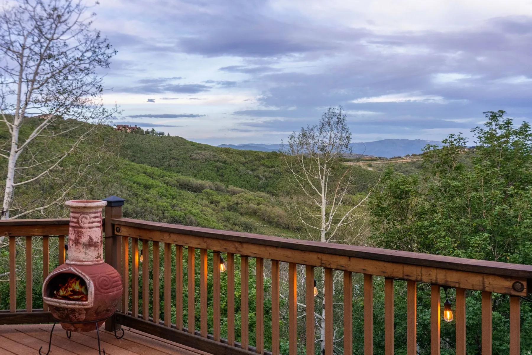 Wood-finish deck with a chiminea, string lighting, and wood railing