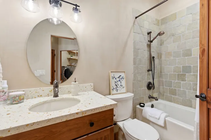Built-in vanity with a composite countertop and integrated sink, a circular mirror, and a wall-mounted light fixture