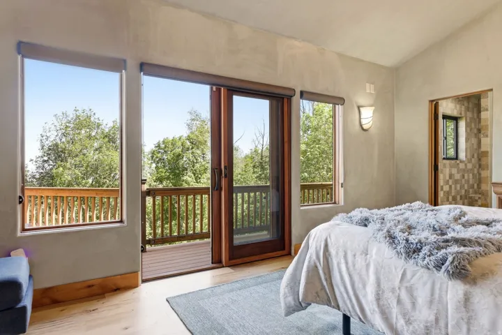 Terrace access with a sliding wood-frame glass door, light wood-finish flooring, and a wall-mounted sconce