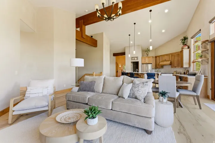 Vaulted ceiling with exposed wood beams, wood-finish flooring, recessed lighting, pendant lighting, and natural wood cabinetry