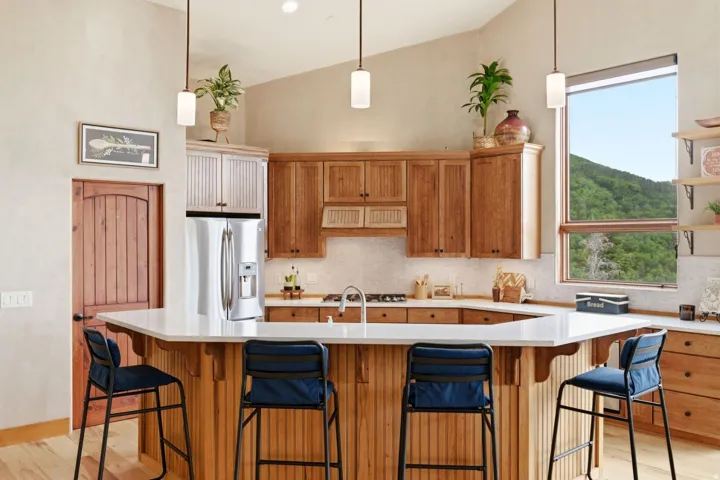 Vaulted ceilings, wood-finish cabinetry, stainless steel refrigerator, white countertops, and integrated shelving