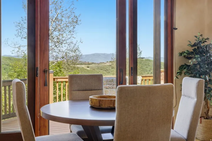 Full-height glass doors with wood frames open to a wood deck railing