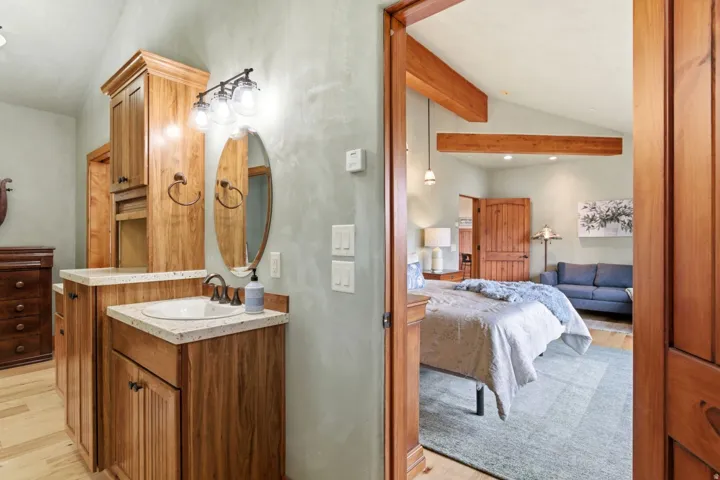 Wood-finish cabinetry and trim, vaulted ceilings with exposed beams, and light wood-finish flooring