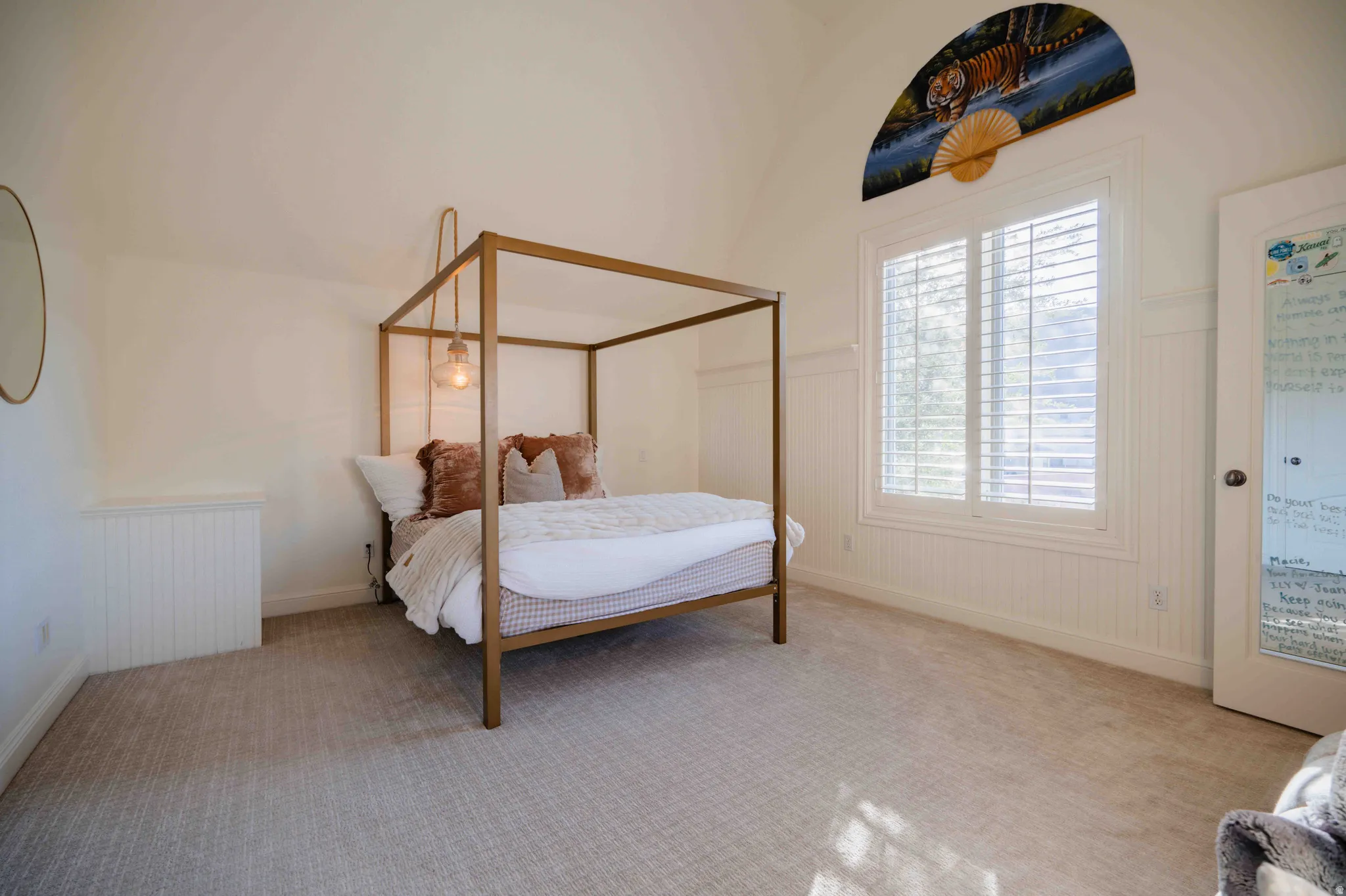 Vaulted ceiling, wall paneling, plantation shutters, and carpeted flooring