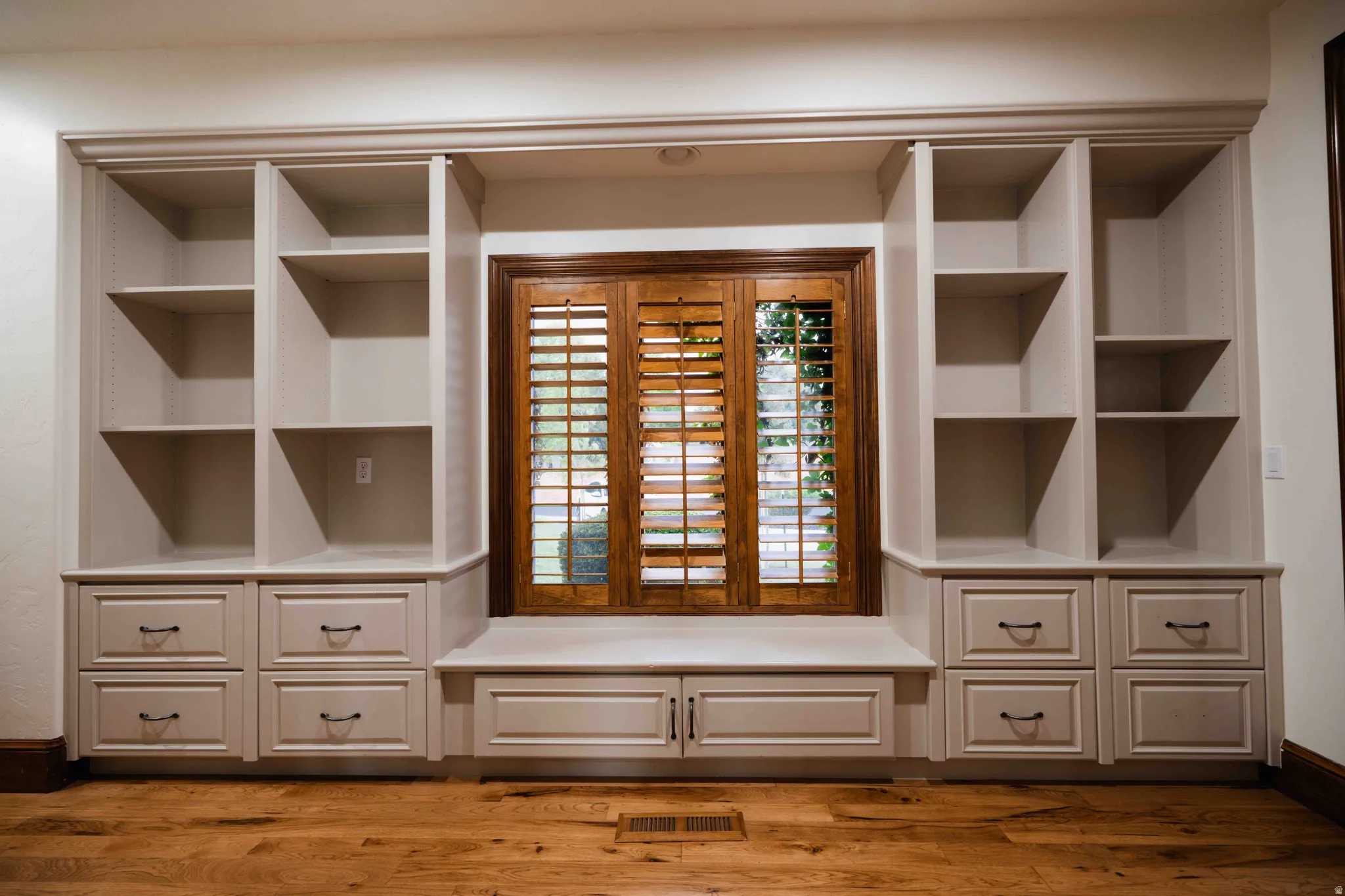 Built-in shelving with adjustable shelves, lower drawers, and a window seat with integrated storage