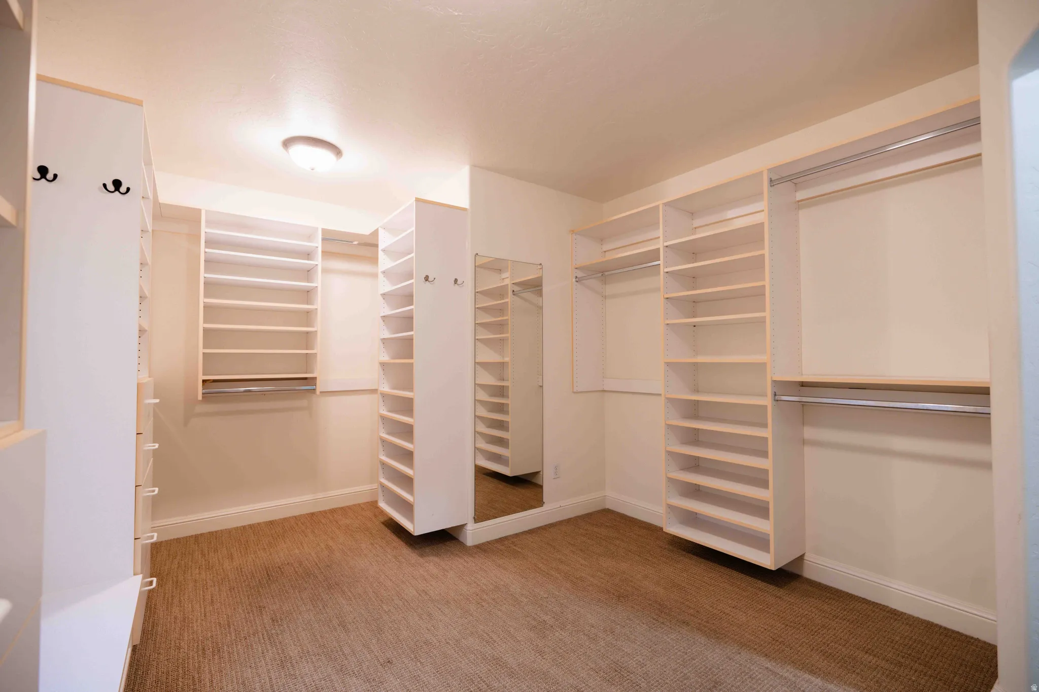 Walk-in closet featuring extensive built-in shelving, multiple hanging rods, and a full-length mirror