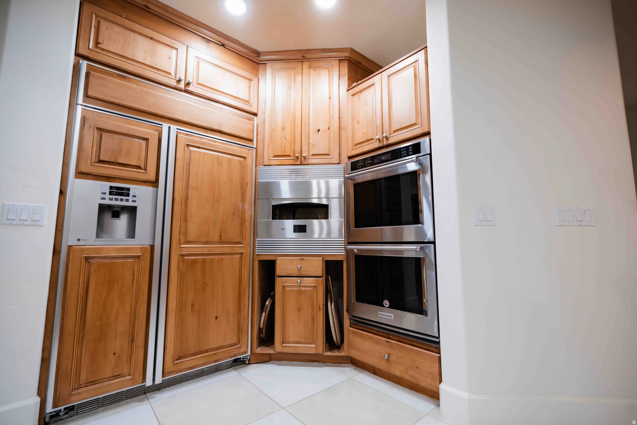 Integrated paneled refrigerator, stainless steel double ovens, built-in microwave, and custom wood cabinetry