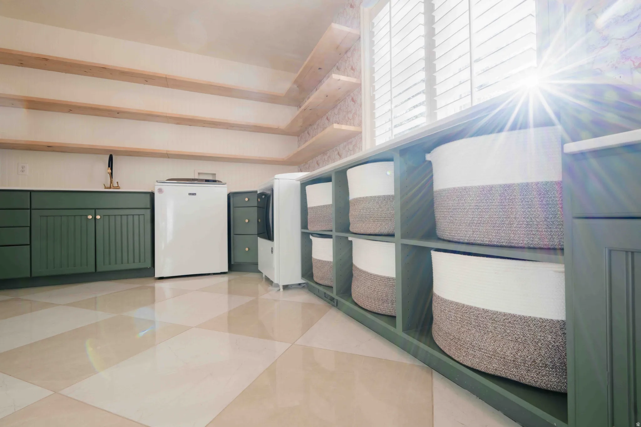 Built-in shelving, checkered floor tiling, wood-finish open shelving, shuttered window, and green cabinetry
