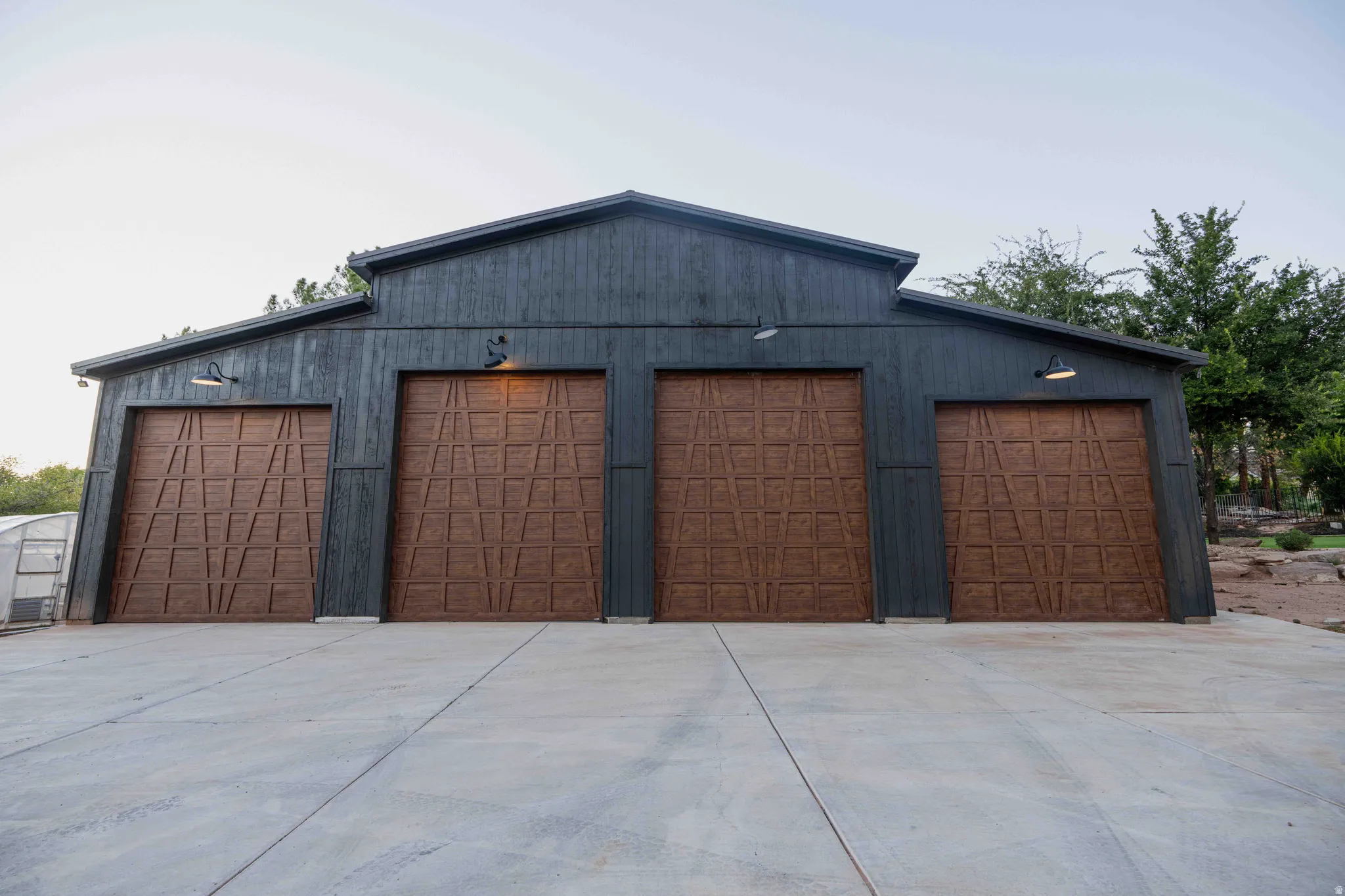 Four-bay garage with contemporary barn-style architecture, dark-stained wood siding, and individual paneled garage doors