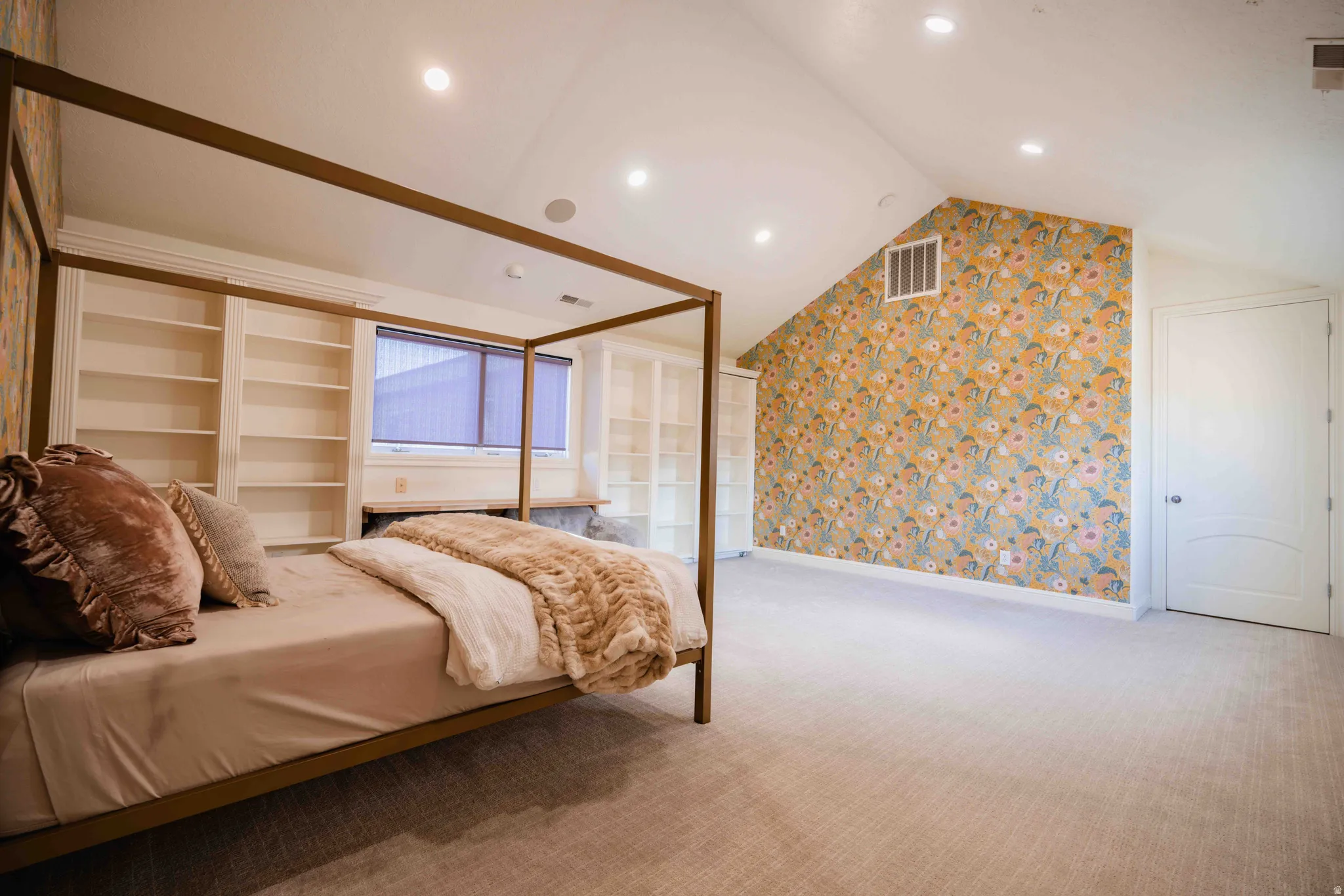 Vaulted ceiling with recessed lighting, built-in shelving, patterned accent wall, and a window with blinds