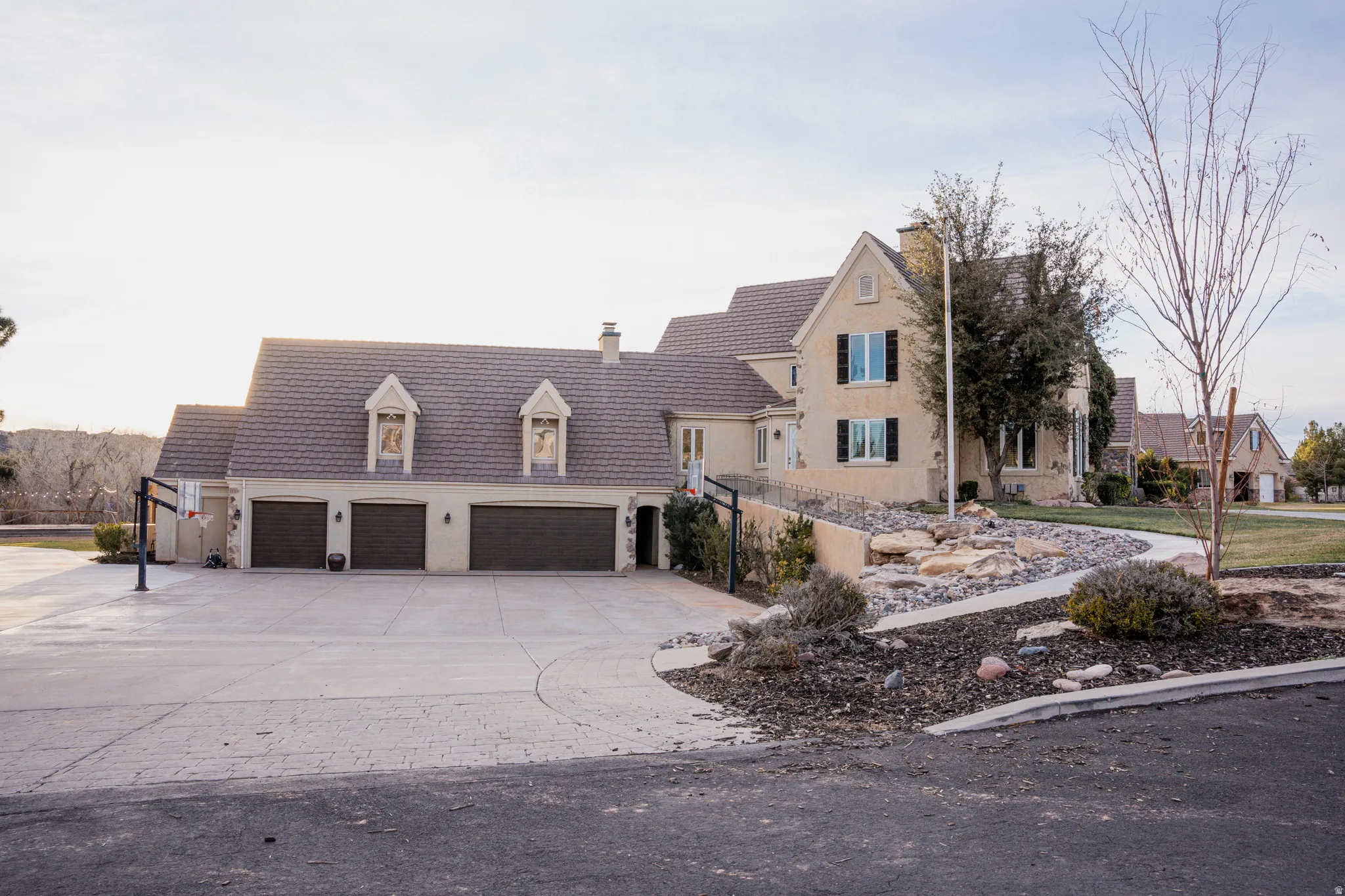 Stucco exterior with a multi-car garage, dormer windows, and a concrete driveway