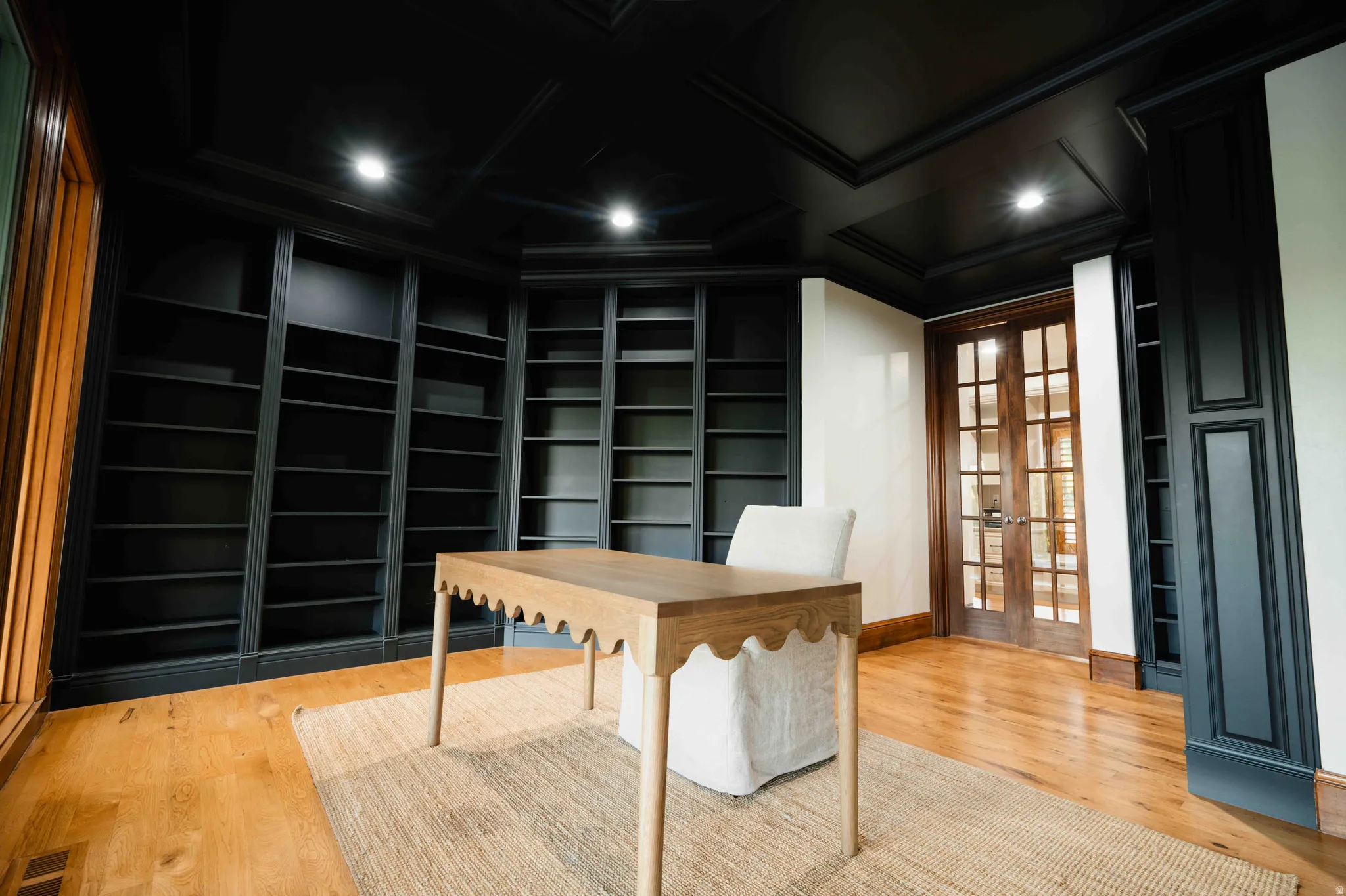 Wood-finish flooring, recessed lighting, built-in shelving, paneled walls, and double French doors