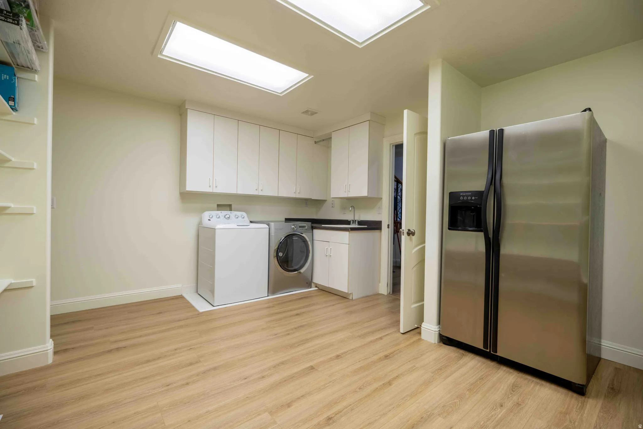 Recessed lighting and skylights illuminate this room with wood-finish flooring