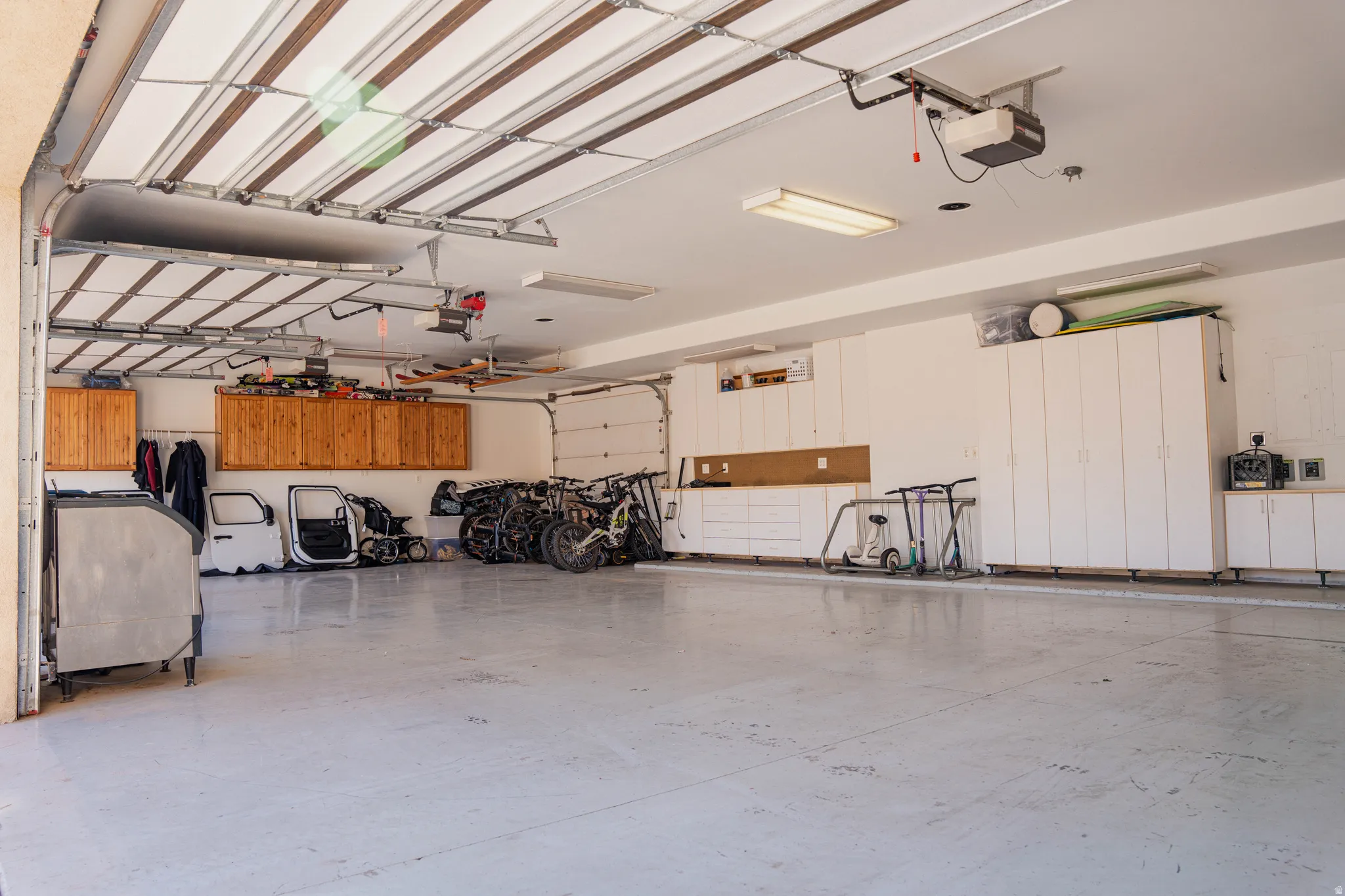 Spacious three-car garage featuring multiple built-in storage cabinets, a workbench with overhead storage, and an automatic garage door opener
