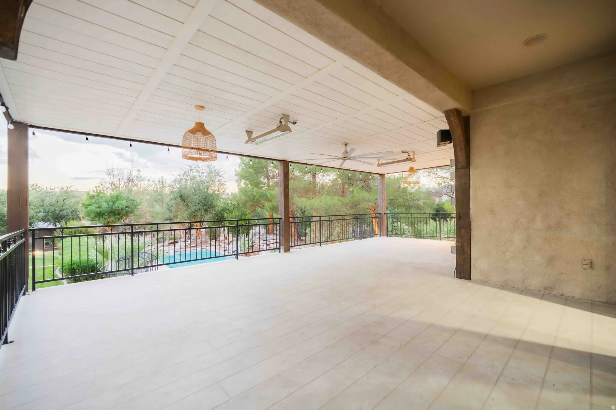 Expansive covered patio with planked ceiling, integrated ceiling fans, and tiled flooring