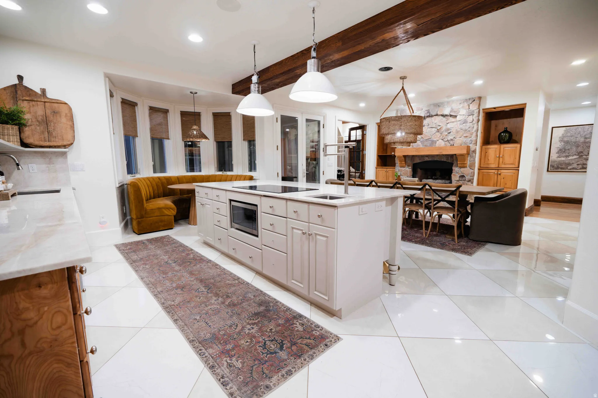 Spacious kitchen featuring a large central island with integrated cooktop, light cabinetry, and stone countertops