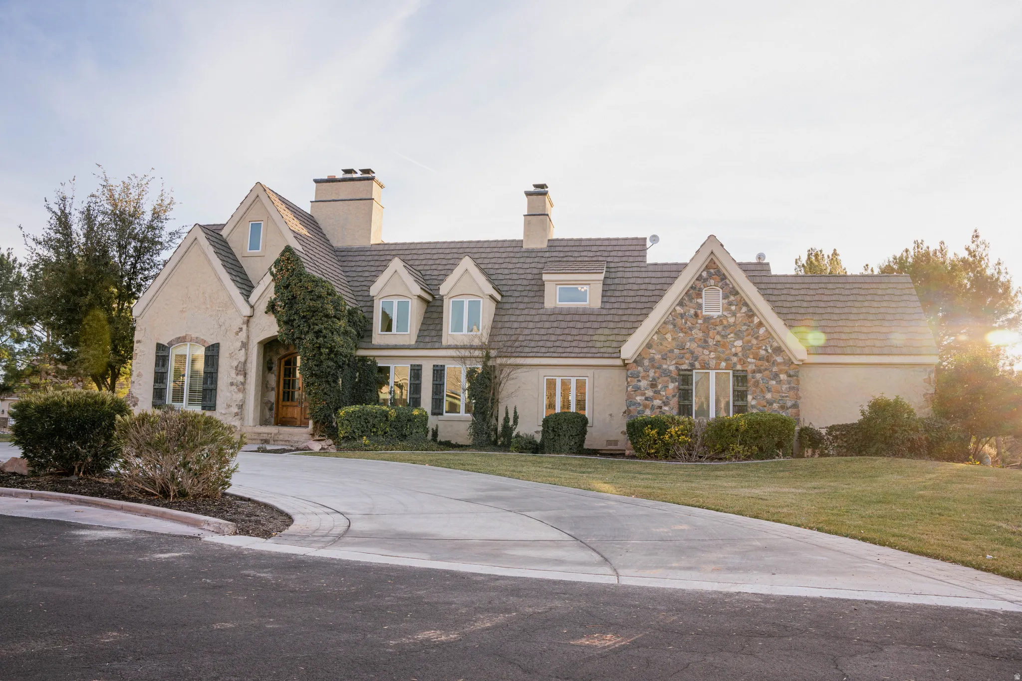 Stucco and stone exterior featuring multiple gables and dormer windows