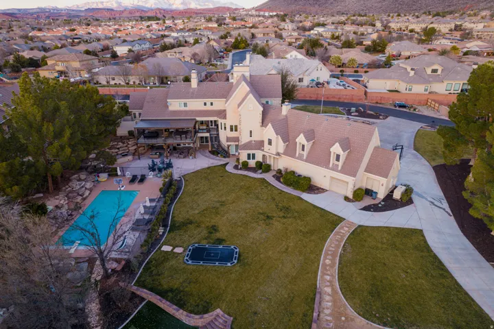 Spacious multi-level property featuring a large lawn, integrated swimming pool, and stone-lined pathways