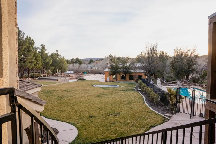 Expansive manicured lawn with a curved paver pathway, mature trees, and a fenced swimming pool