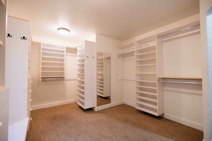 Walk-in closet featuring extensive built-in shelving, multiple hanging rods, and a full-length mirror
