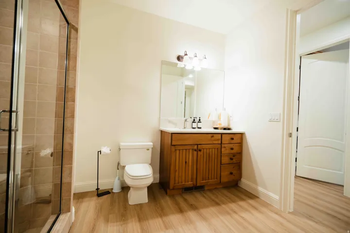 Glass-enclosed shower with tiled surround, wood-finish flooring, and a vanity featuring a wood cabinet and countertop